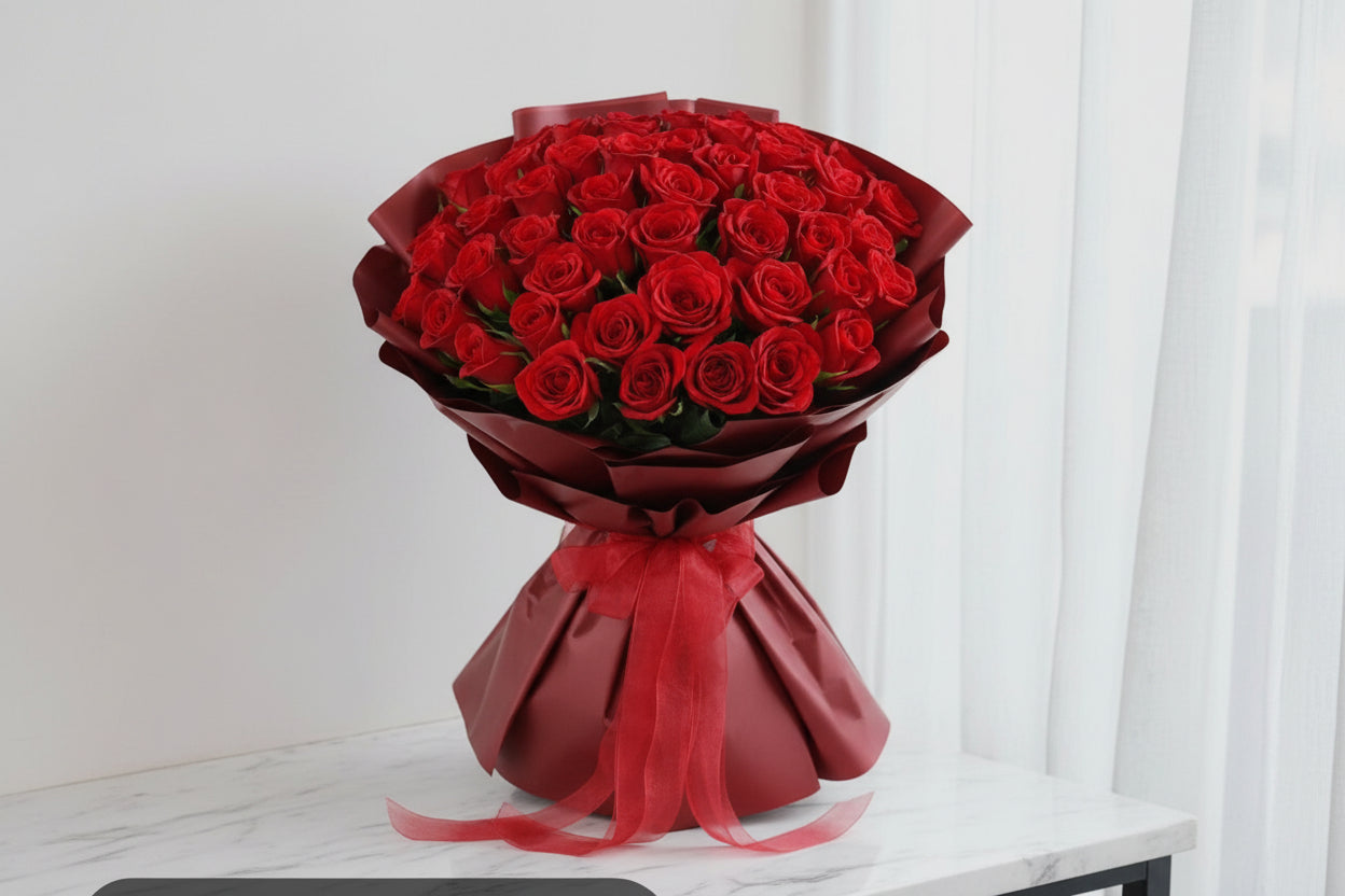 Bouquet of red roses wrapped in black paper with a red bow on a white background