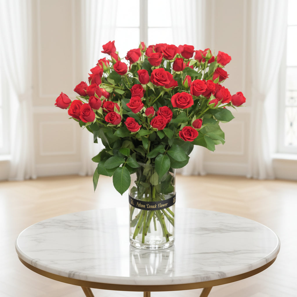 Bouquet of red roses in a clear vase on a black surface with a white background