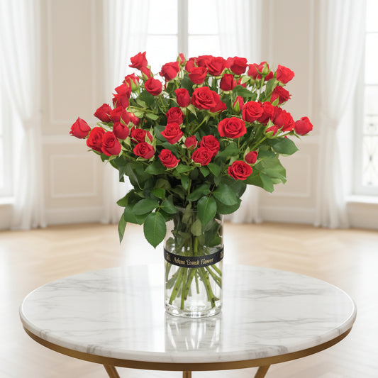 Bouquet of red roses in a clear vase on a black surface with a white background