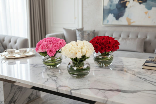 Three small glass vases with pink, white, and red flowers on a white background