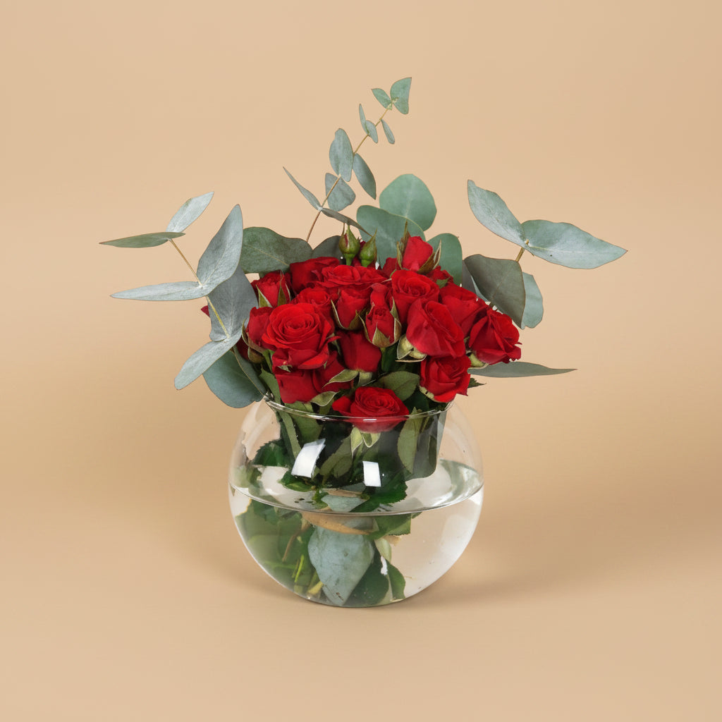 Bouquet of red roses with eucalyptus in a clear glass vase on a white background