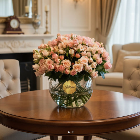 Bouquet of pink roses in a clear vase on a reflective surface