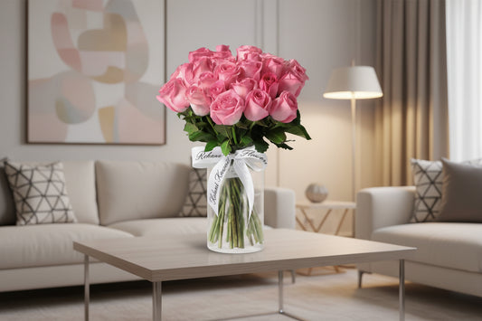 Bouquet of pink roses in a clear vase with a white ribbon on a light gray background