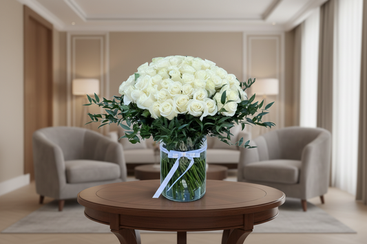 Bouquet of white roses with green leaves in a clear vase on a white background