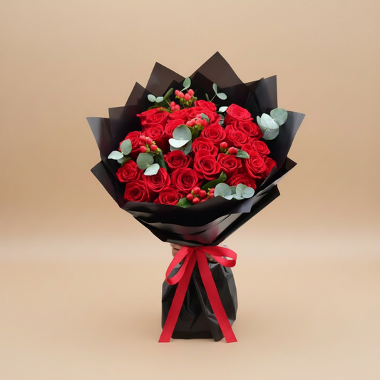Bouquet of red roses wrapped in black paper with a red ribbon on a white background