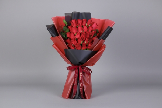 Bouquet of red roses wrapped in black and red paper on a white background