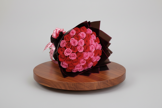 Bouquet of red and pink roses in a black box with a pink bow on a white background